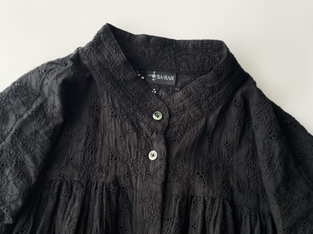 Sa-Rahの洋服。黒の総レース刺繍のスタンドネックギャザーのフレンチスリーブワンピースのフラットレイ画像。襟元をクローズアップした写真。