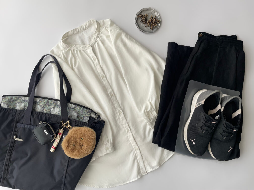 40代女性の2025年6月下旬コーデ。GUの白ブラウスにGUのリネン混パンツ（黒）、PUMAのPROWLを合わせている。LeSportsac×V＆A博物館コラボのネイビーのコラプシブルトートやFUA accessoryのイヤリングを並べたフラットレイ画像。