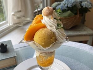カフェネイビー（Café　NAVY）のマンゴーParfait。2025年6月撮影。背景には紫陽花の寄せ植えバスケットが映っている。