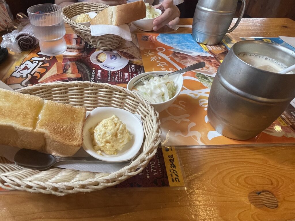 コメダ珈琲店のモーニングサービス。山食パンと手作りたまごペースト、マーガリン。たっぷりのアイスミルクコーヒーとコールスローサラダが並ぶ。