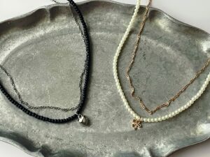 GUの390円ネックレス2種類。左は黒ビーズとハートモチーフのネックレス、→はパールとリボンモチーフのネックレス。