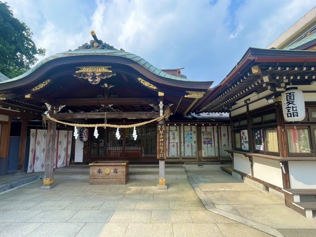 琴平神社の儀式殿の写真。夏詣期間中であることが解る提灯がさがっている。2025年7月撮影。