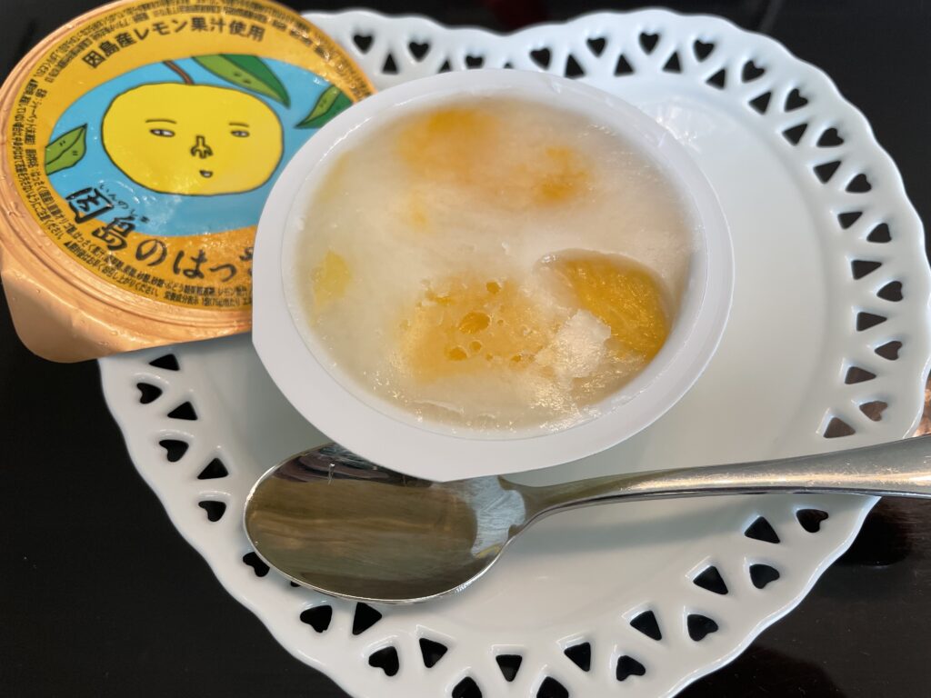 「因島のはっさくシャーベット」がハート型でレースのような縁取りの陶器のお皿にのせてある。蓋を開けた後の写真。