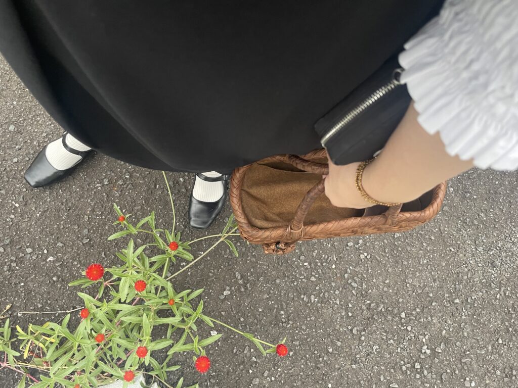 40代女性の2025年7月中旬コーデ、ユニクロの白のギャザーブラウスとノアールレーベルのジャンパースカートを合わせている。手には五十嵐三美さん作山ブドウのかごバッグを持っている足元写真。