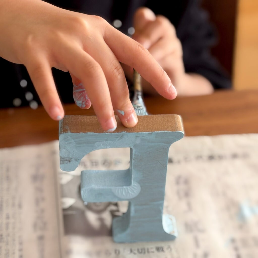 ブルーのアクリル絵の具をアルファベットのオブジェに塗る様子