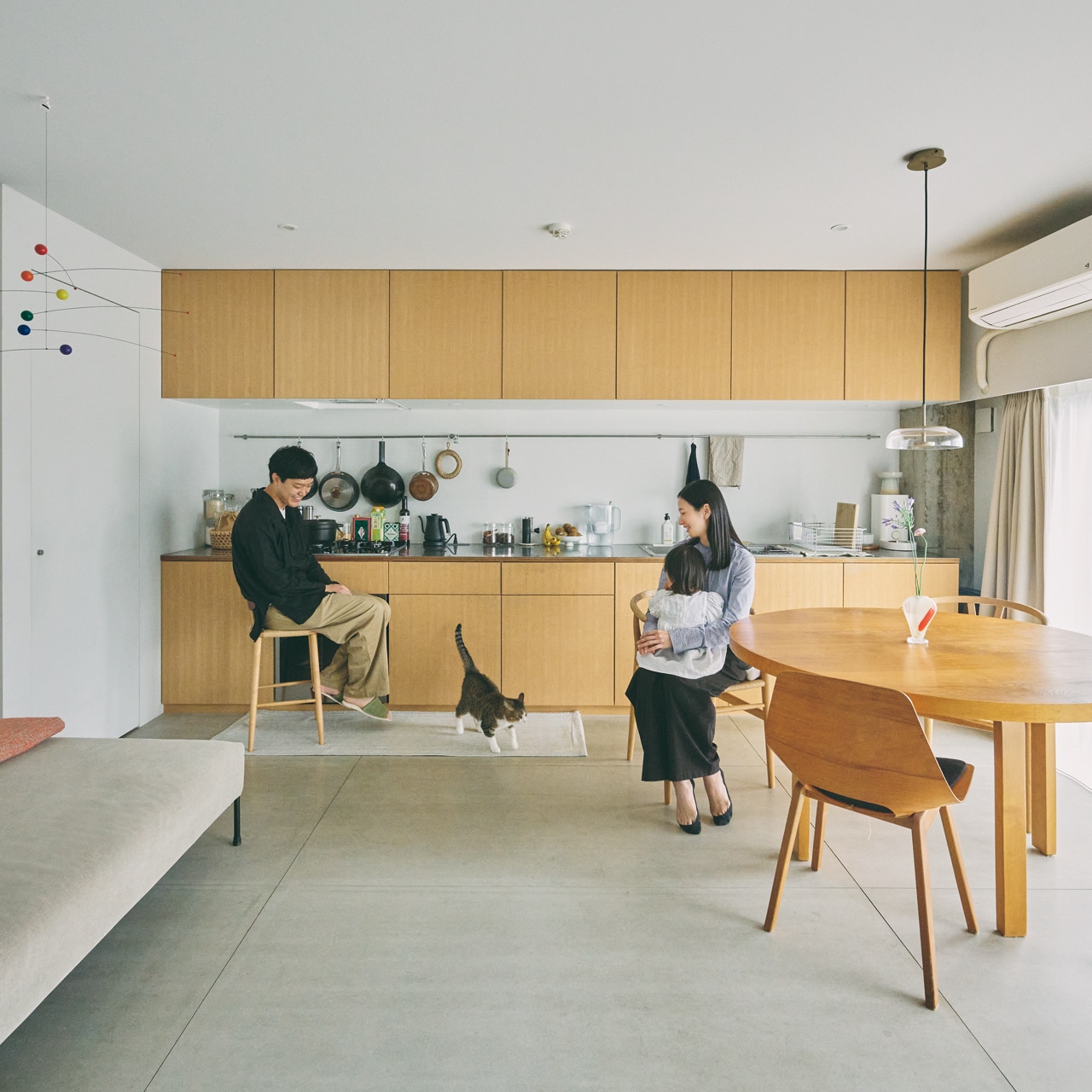 LDKの一辺に壁付けした、幅4mを超えるキッチンが圧巻。料理好きな吉田さんだけでなく、来客も含め、みんなで気軽に料理をしたりくつろいだりできるようにという思いから生まれた。吊り戸棚は換気扇の奥行きに合わせてすっきり。