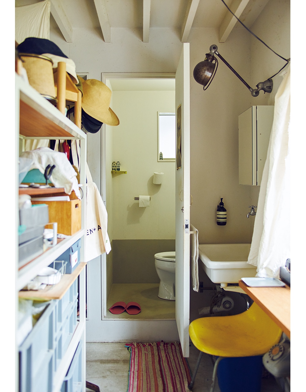 1階は夫の仕事場と、トイレ、洗面所、シャワー室など、水回りが集まる。高さのある棚にものを収めて、玄関からの目隠しに。