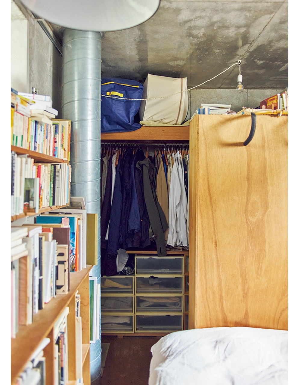 寝室奥にある夫婦2人の服や季節ものが収まったクローゼット。木製の棚が目隠しに。