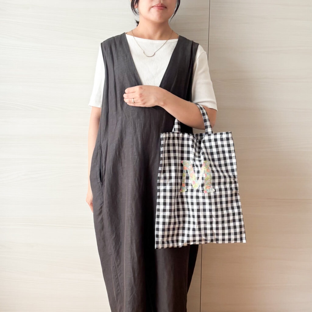 ギンガムチェックのトートバッグを短い持ち手でひじ掛けした様子