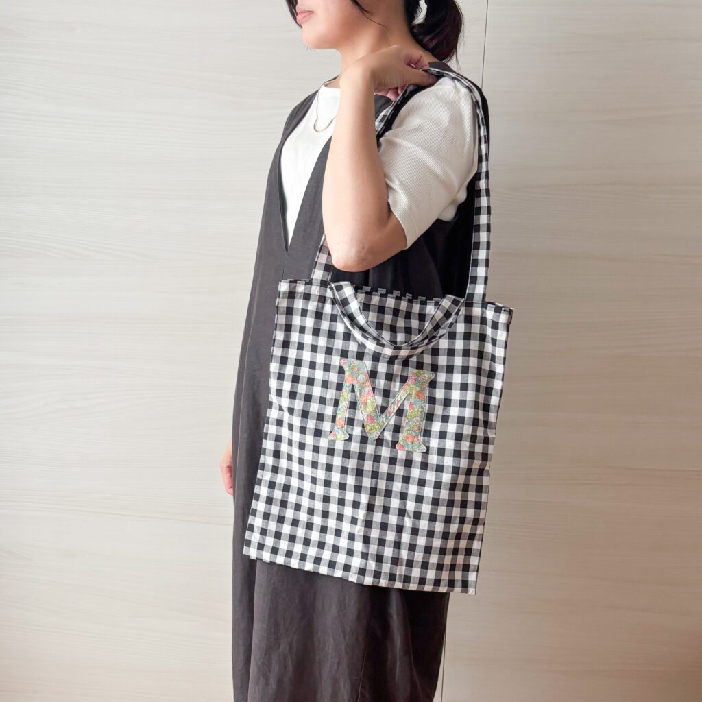 ギンガムチェックのトートバッグを長い持ち手で肩掛けした様子