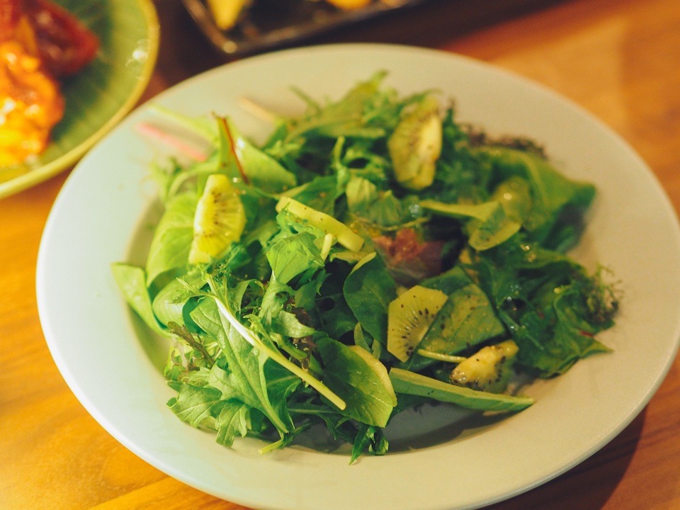 白いお皿のうえのベビーリーフとキウイのサラダ