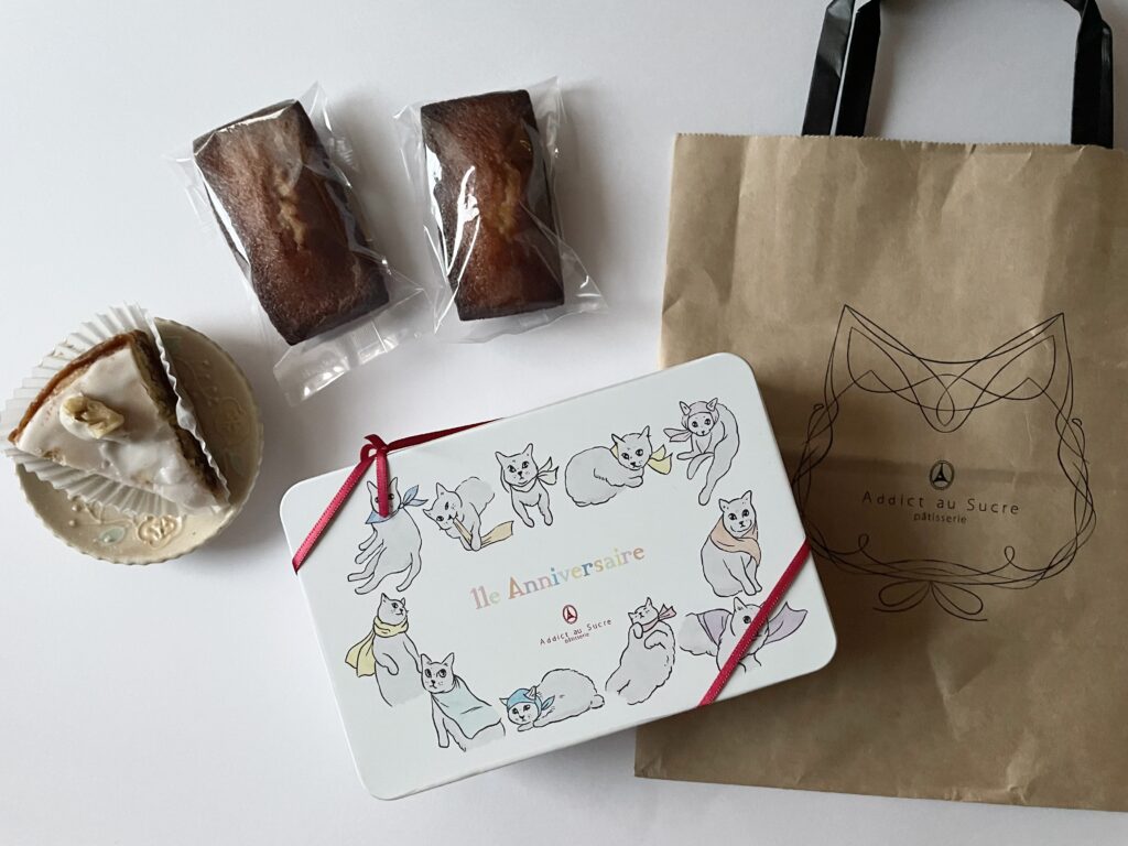 アディクト・オ・シュクル（Addict au Sucre）での購入品。クッキー缶やフィナンシェ、パスティソーというクルミを使った地方菓子が並ぶ。