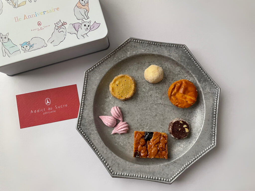 アディクト・オ・シュクル（Addict au Sucre）11周年記念缶「オーンズ シャ」のクッキーを種類ごとにアルミプレート上に並べたもの。