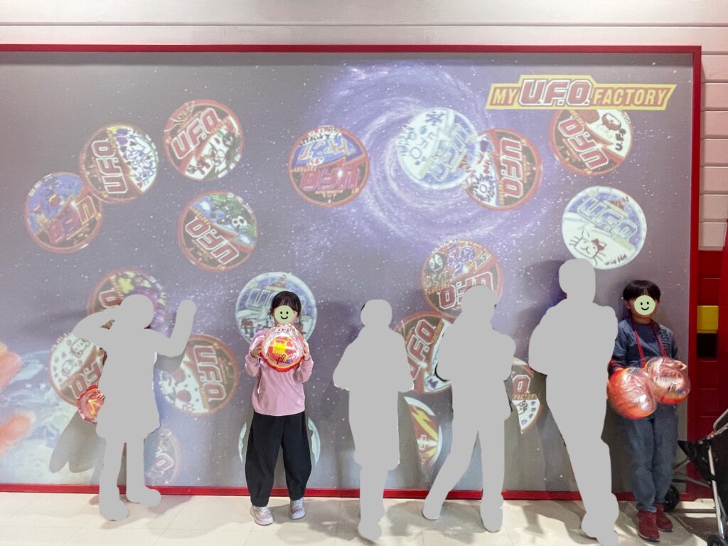 6人でマイU.F.O.を手に持って、スクリーン前で記念撮影