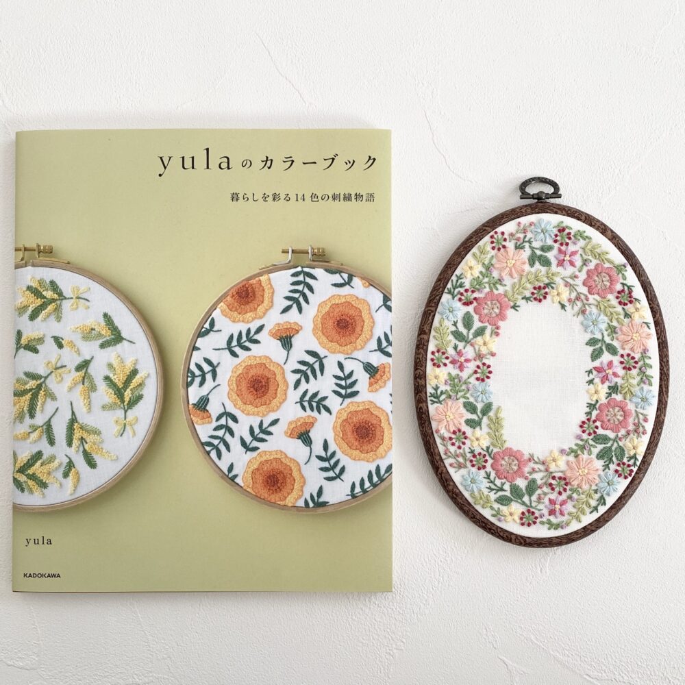 『yulaのカラーブック 暮らしを彩る14色の刺繍物語』の本と完成した『カラフル百花園』