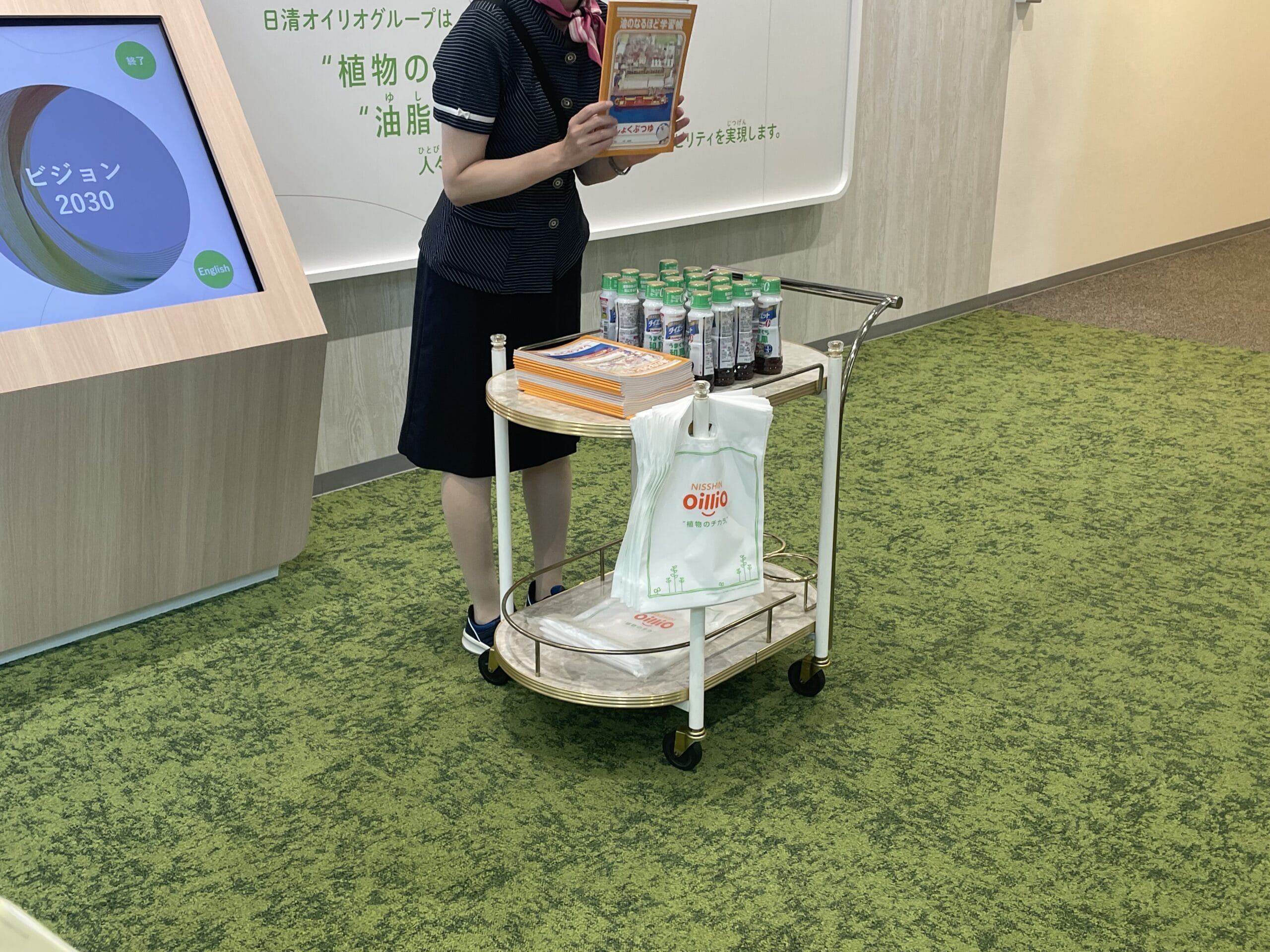 日清オイリオの横浜磯子事業場内、ウェルネスギャラリーで工場見学のお土産が渡されるシーン。