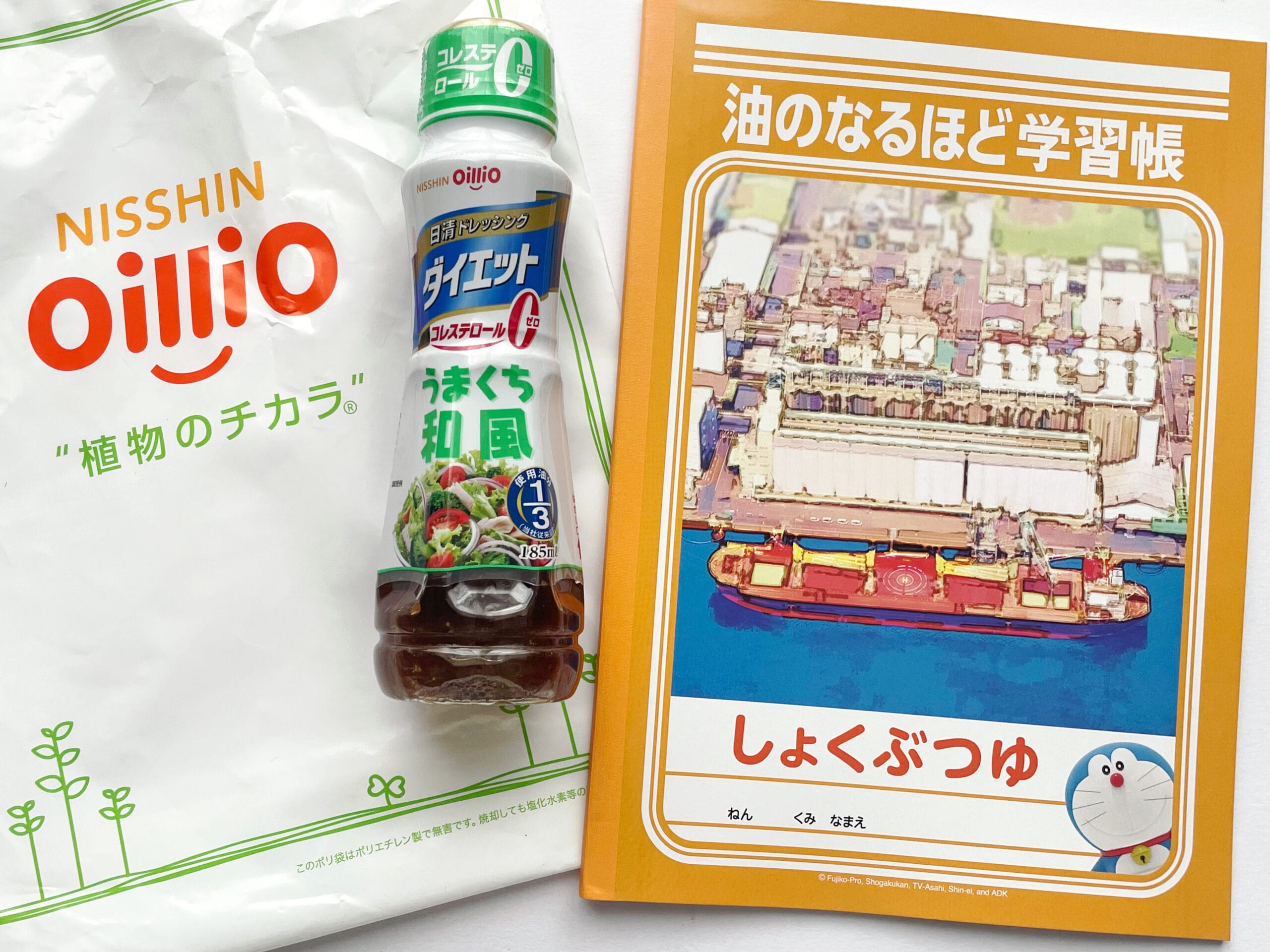 「日清ドレッシング ダイエット うまくち和風 185mL」と「油のなるほど学習帳」が並べられた写真。日清オイリオ磯子事業場での「夏の工場見学」ツアーのお土産。