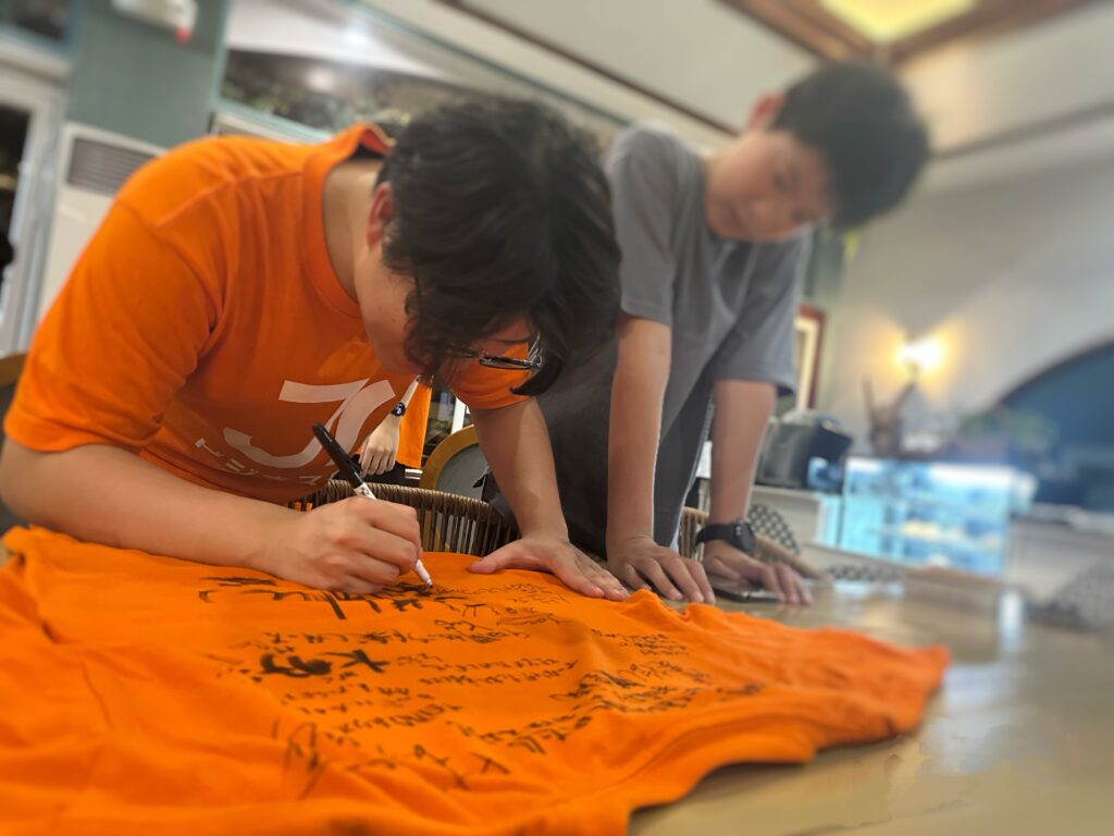 最終日、友達同士やお世話になったメンターとキャンプTシャツにメッセージを書き合う姿