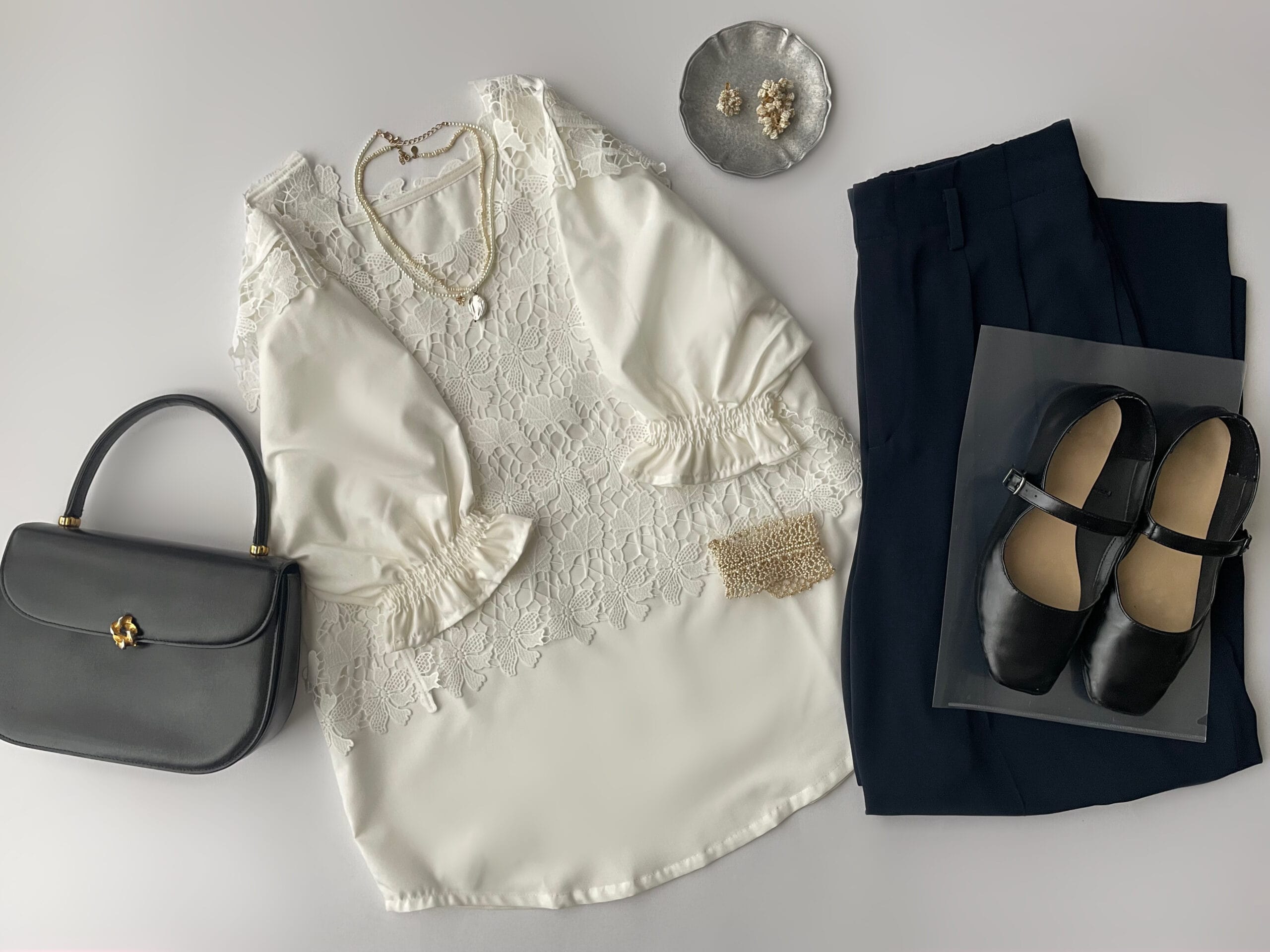somari imaginationの白のレースベスト＋白のキャンディスリーブブラウスのセット使い、ネイビーのタックパンツと合わせたフラットレイ画像。