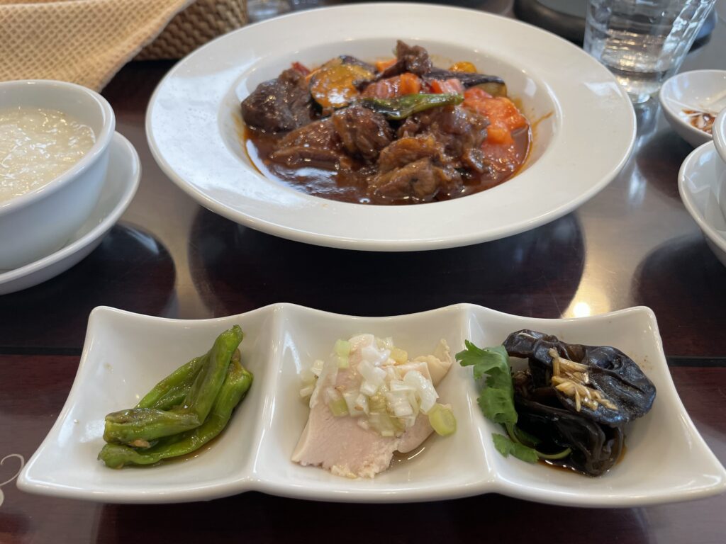 中華レストランでの一コマ。牛肉とトマトの甘酢あんかけがメインのランチセット。手前に前菜3種類が置かれている。