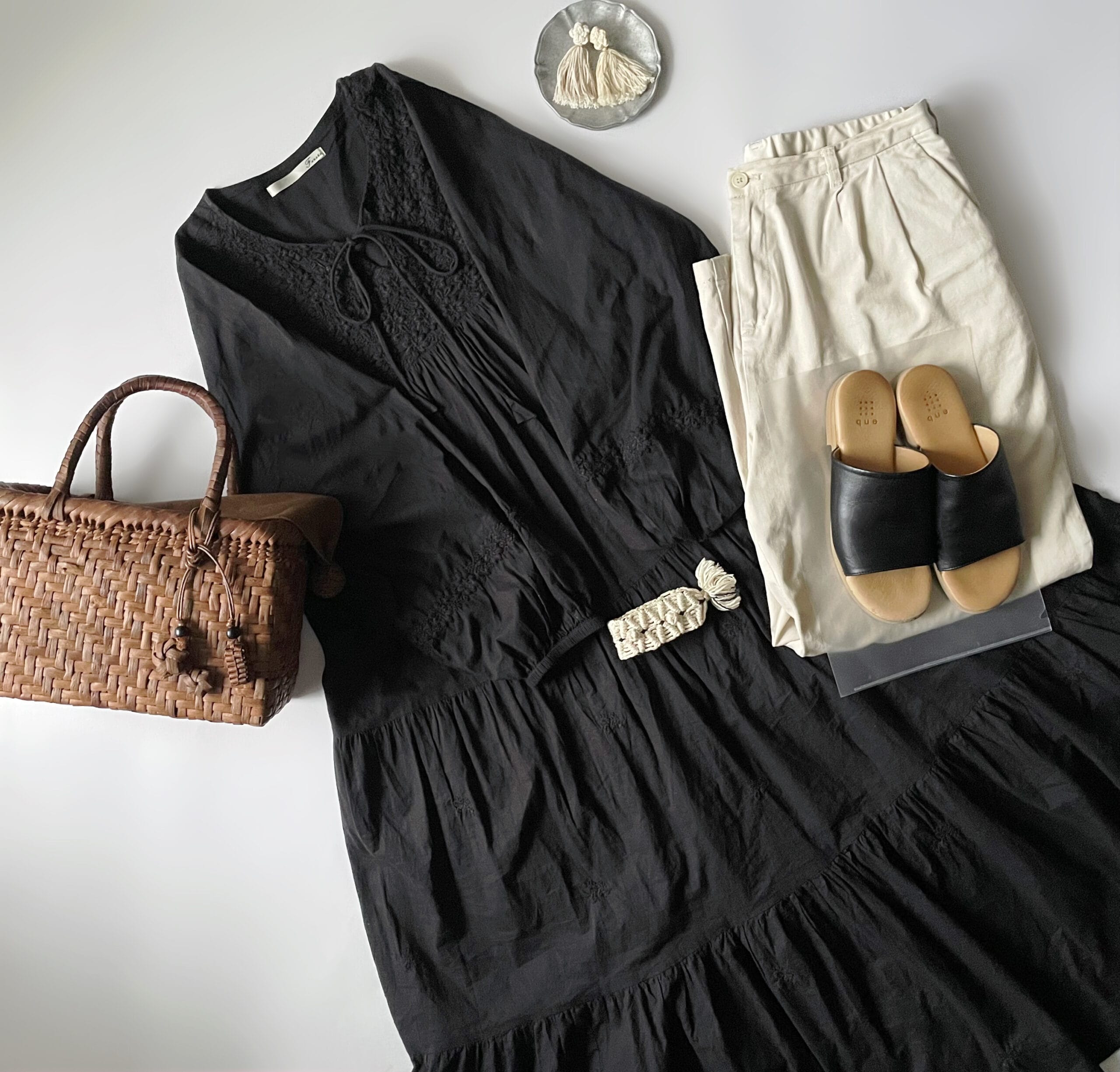 40代女性の2025年8月下旬~9月初旬コーデ、Fanakaの黒の刺繍ワンピースに無印良品の白のリネンタックパンツを合わせているフラットレイ画像。