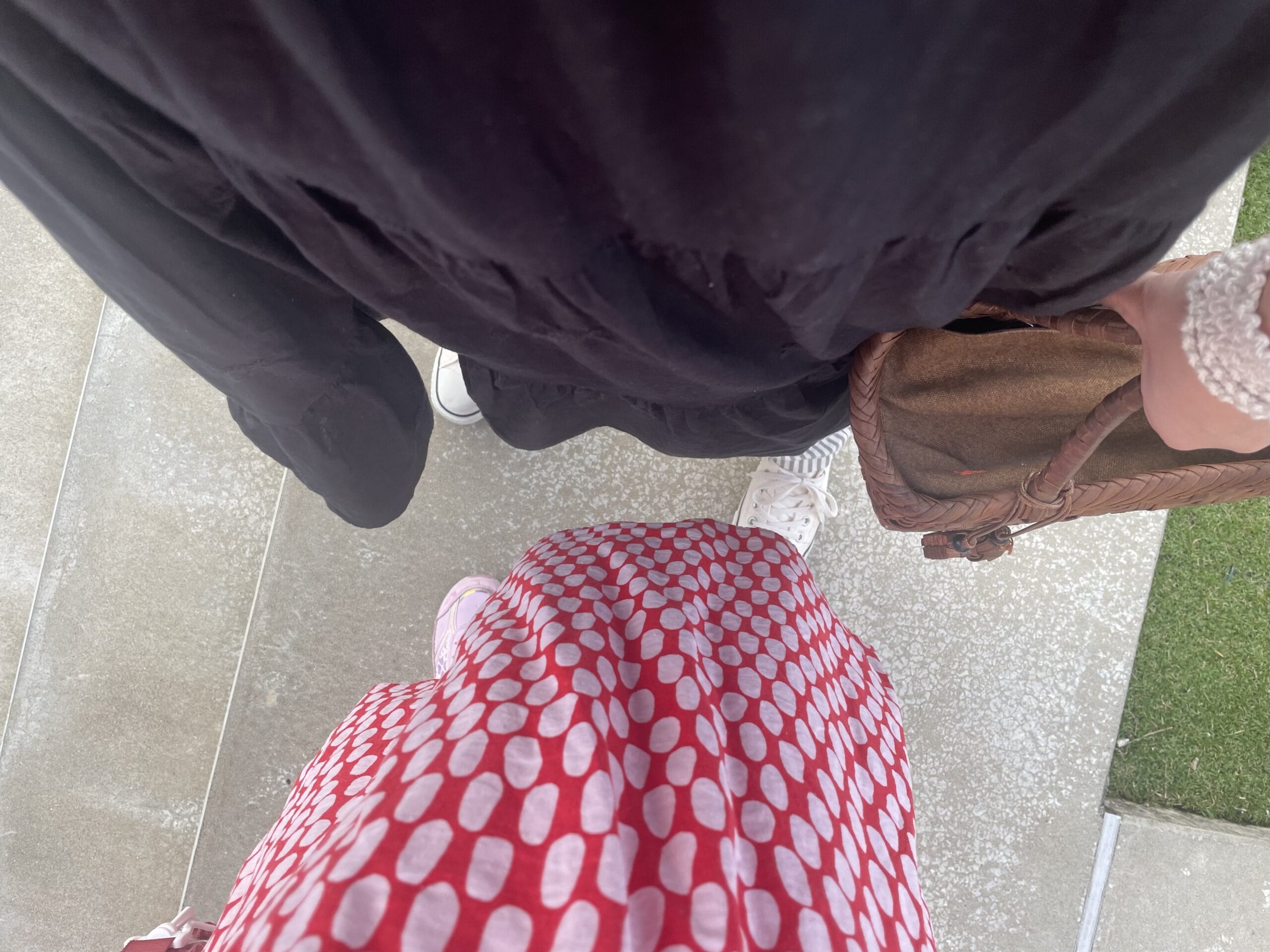 40代女性の2025年9月中旬コーデ、足元写真【その1】。Fanakaの黒の刺繍ワンピースにGUのグレーストライプのパンツを合わせている。コンバースの白のローカットを履いている。