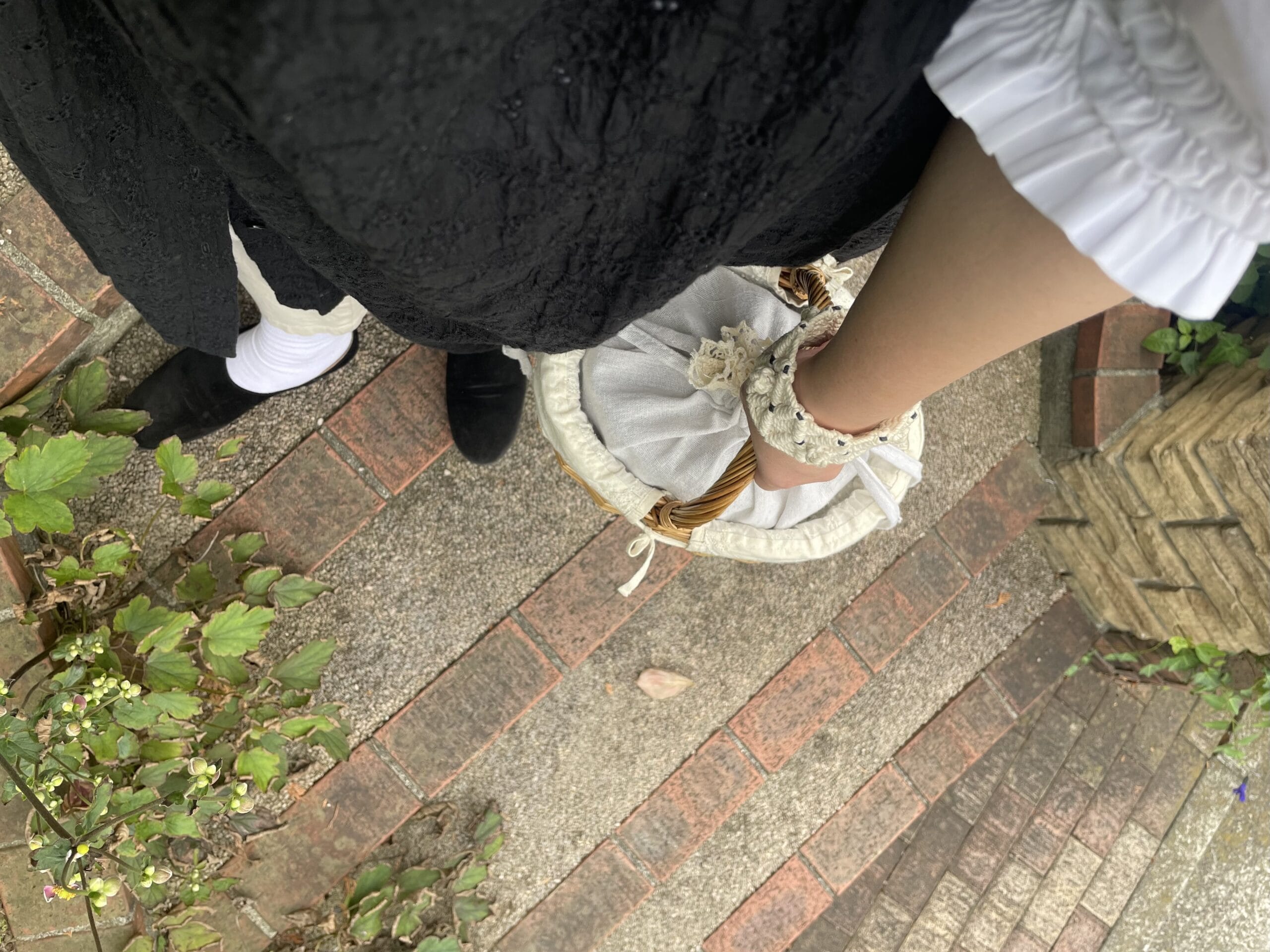 40代女性の2025年9月中旬コーデ、足元写真【その2】。ユニクロの白のギャザーブラウスと無印良品のリネン混パンツの上にSarahのジレ風の刺繍ワンピース(黒)を羽織っている。queのベロア素材の黒のplainシューズを履いている。SamansaMos2×モデルのkazumiさんコラボのかごバッグを持っている。