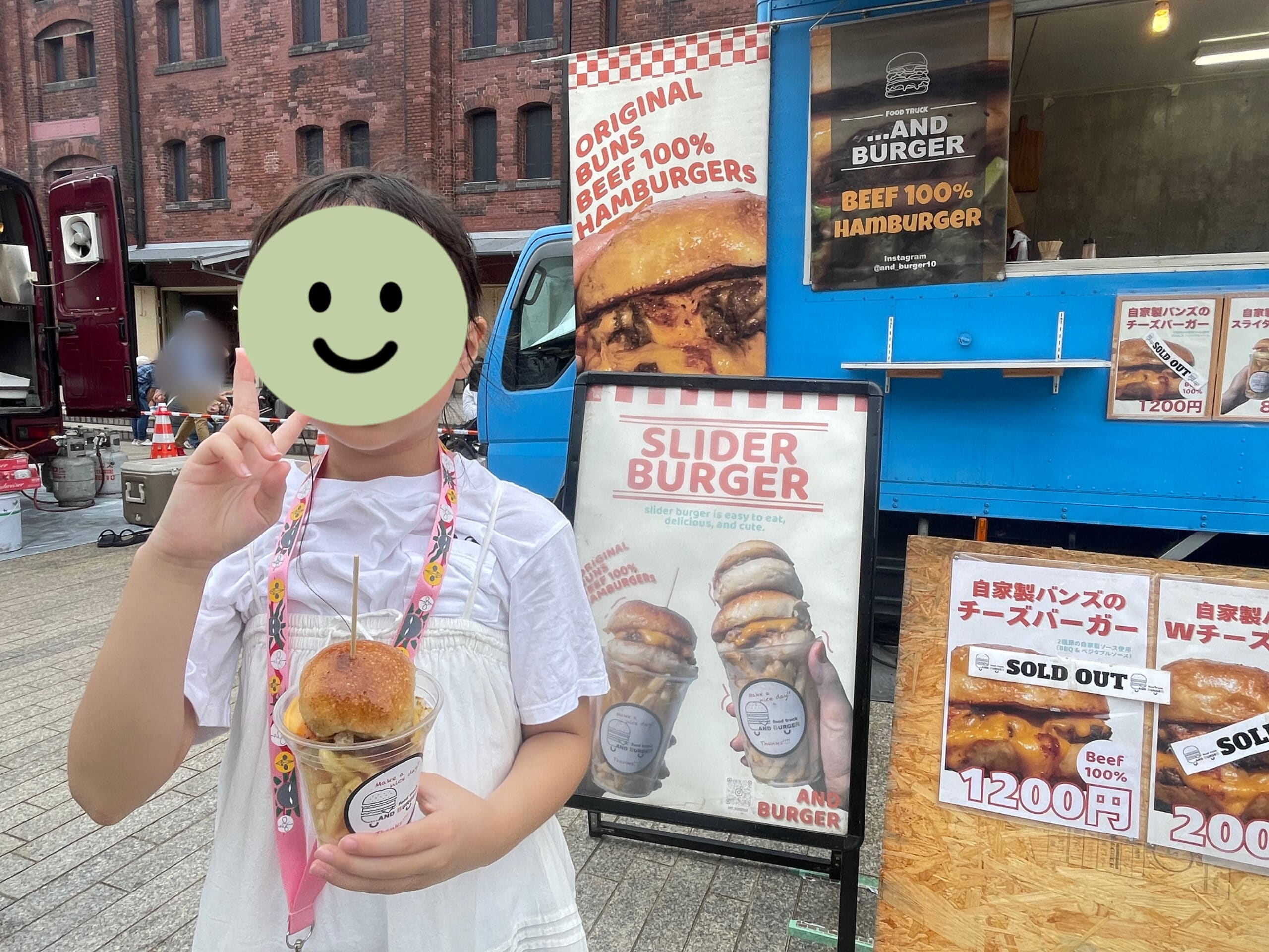 ハンバーガーフェス2025での「AND BURGER」の自家製バンズのスライダーバーガーを持つ小3女子。