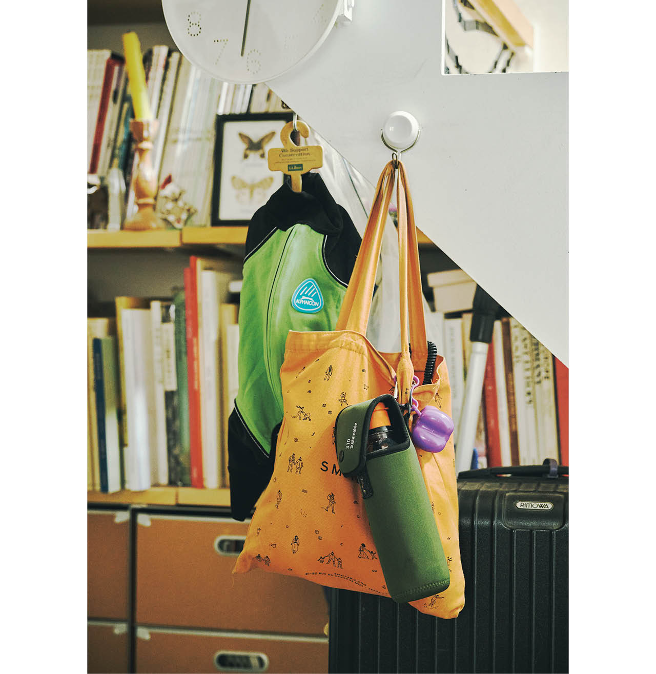 散歩時のマナーセットのうんち袋とウォーターボトルはバッグの取っ手に引っかけ、すぐ出せるように。玄関を入ってすぐの階段わきに吊るして収納。雨の日は「ALPHAICON」のレインコートを。