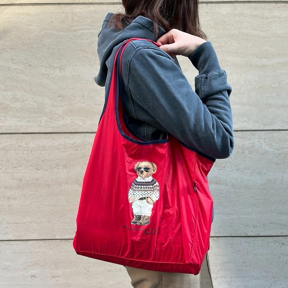 ノルディック柄のニットに白シャツをイン、ボトムスには白いパンツでサングラスをかけた洒落た冬コーデに身を包んだポロベア　レインバッグ