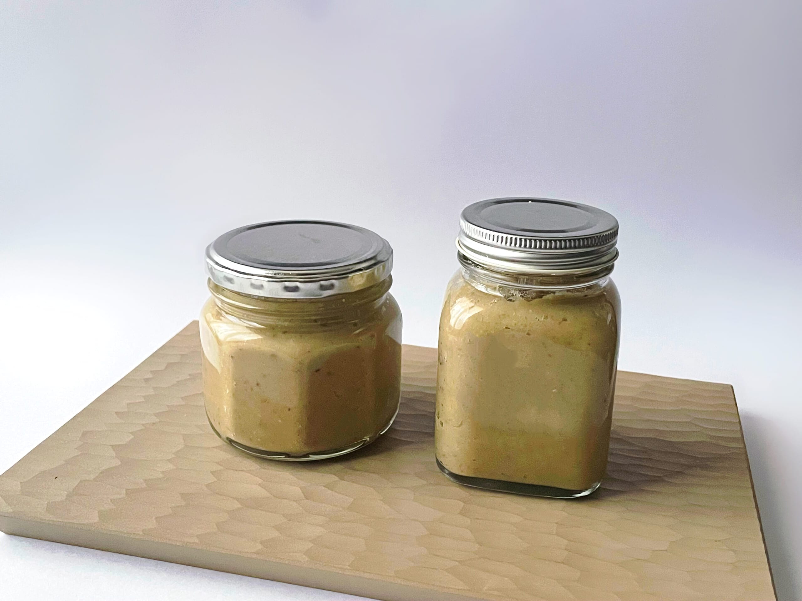 榎本美沙さんレシピ「栗のミルクジャム」を40代主婦が作り、セリアの保存瓶に入れた写真。瓶は2つ並んでいる。下に白漆の刳り板が敷かれている。