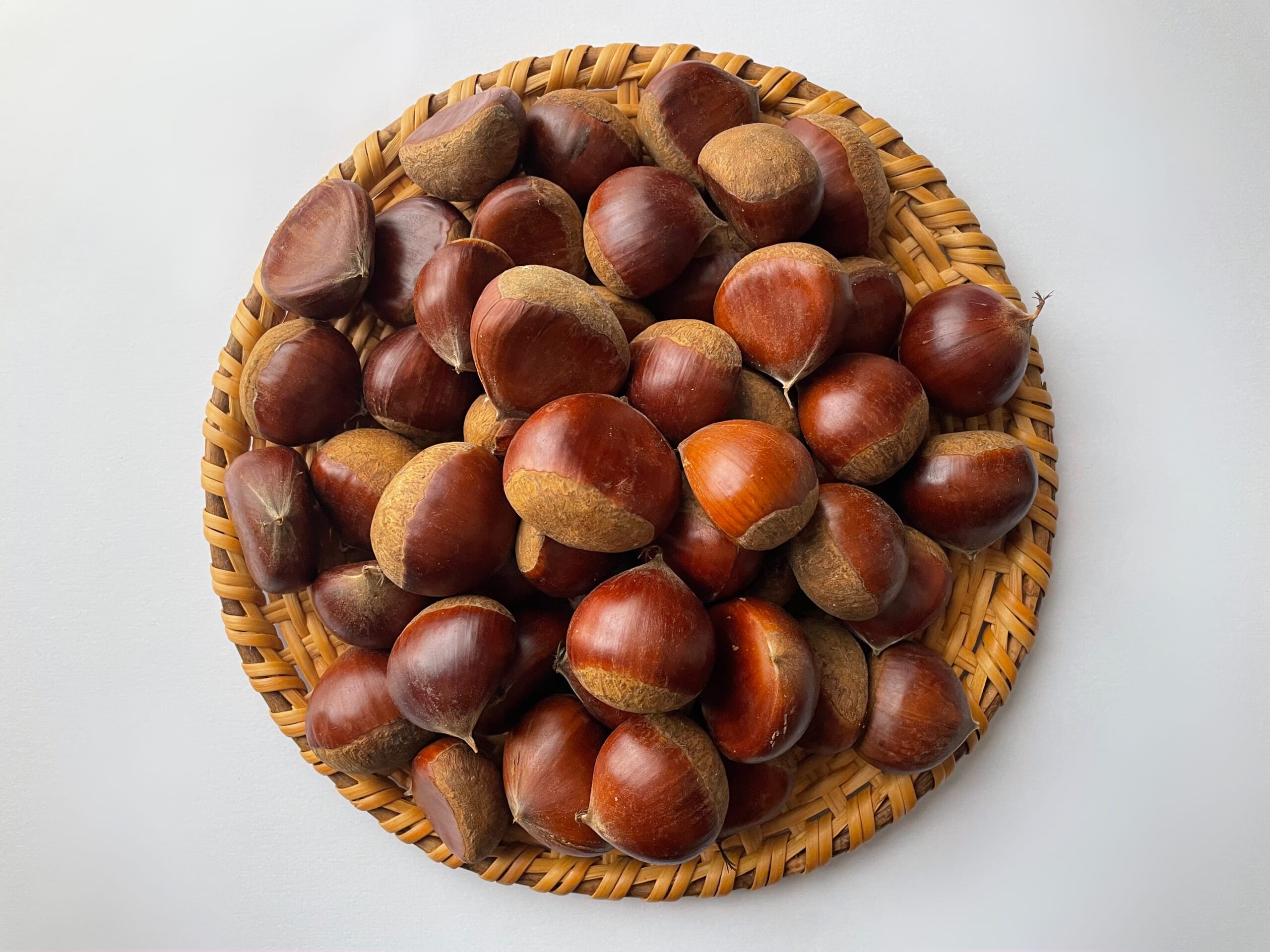ざるの上に生の栗がのっている写真