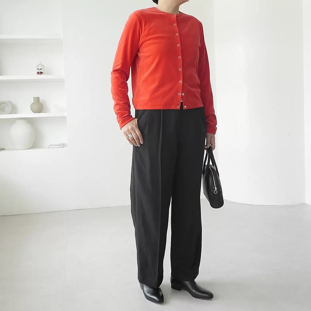 赤いベロアカーディガンをトップス使いしてブラックのスラックスを履いたコーディネート