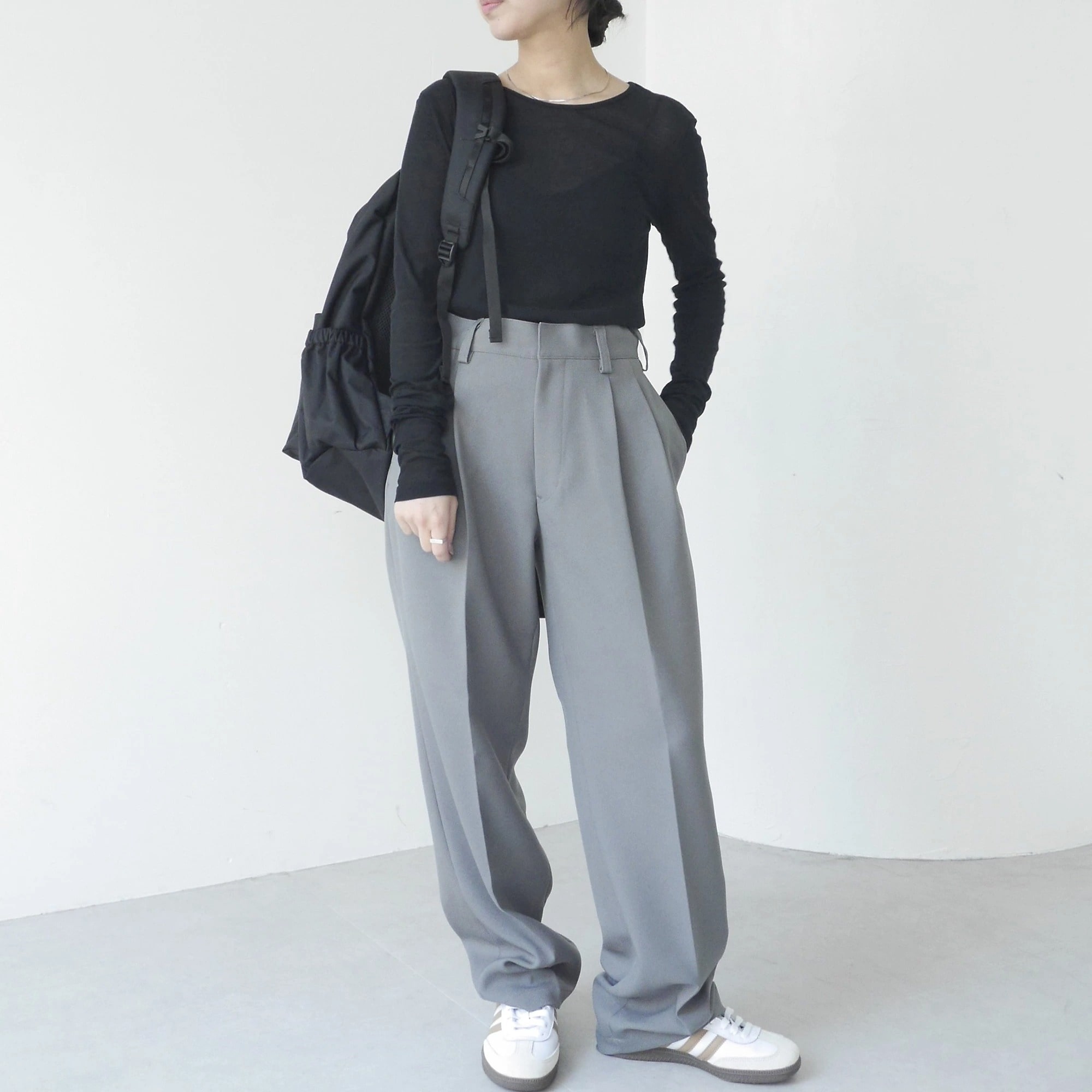 黒のシアーニットトップスにグレーのスラックスを合わせたコーディネート