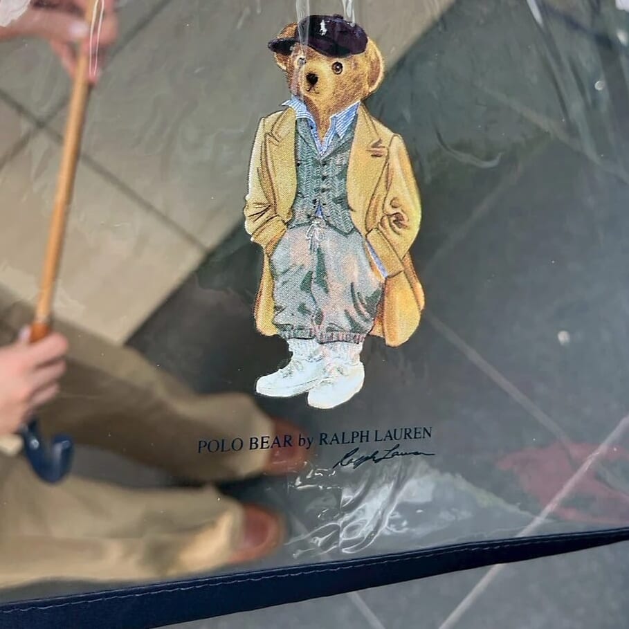 ストライプのシャツにヘリンボーンのジャケット、パンツはグレースウェットでラフにきめて、キャメルのコートにネイビーのキャップ　ポロベア　ビニル傘　ネイビー