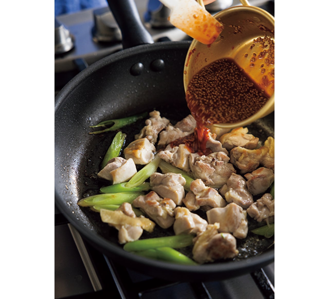 蒸し焼きした鶏肉に味つけする様子