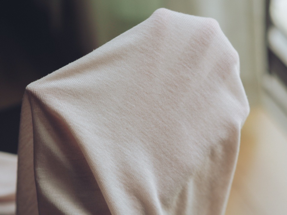 GUのソフトクルーネックTに手を差し込んで透け感を確かめている