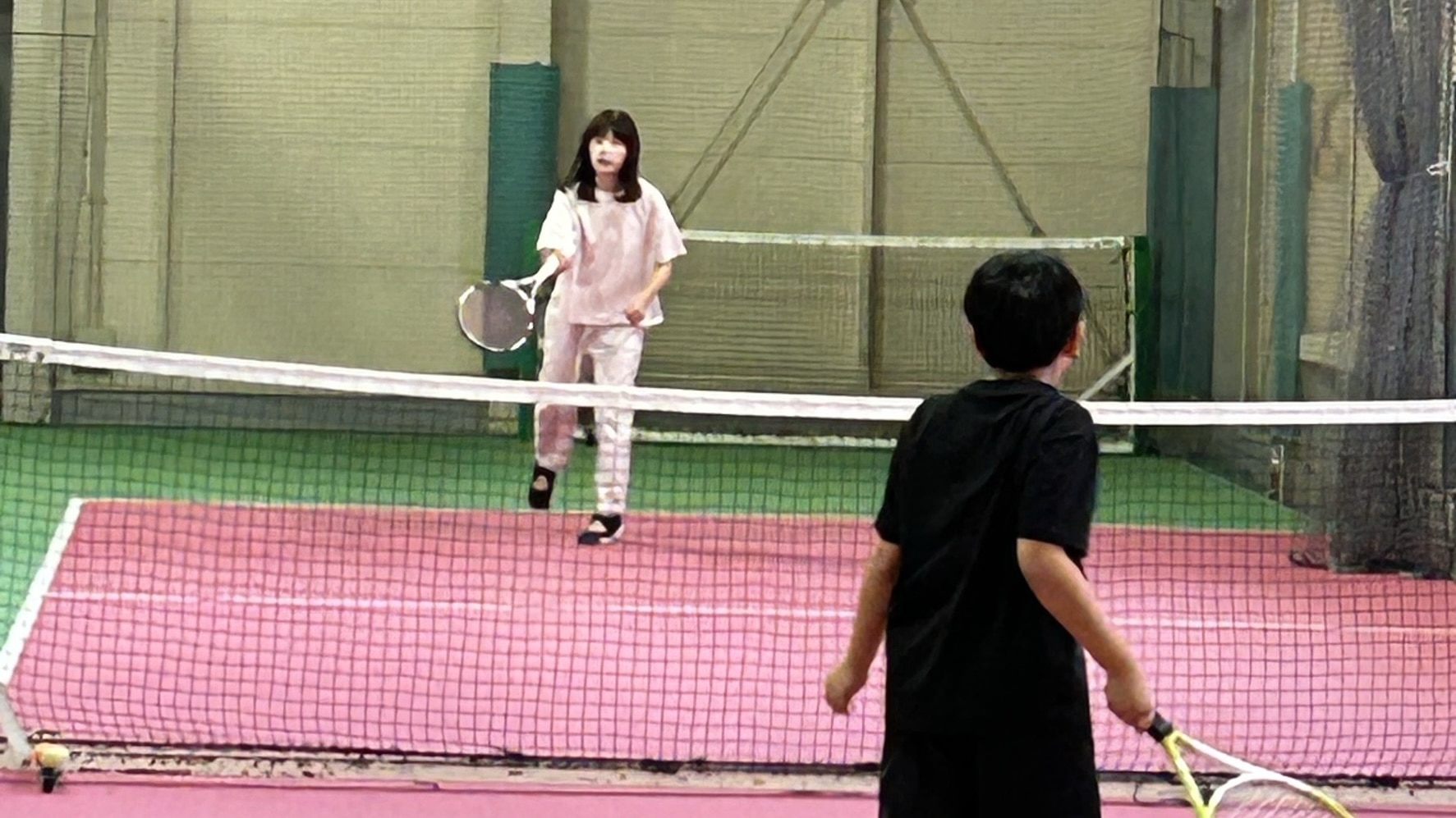 40代女性と小学生がテニスの練習をしている風景。