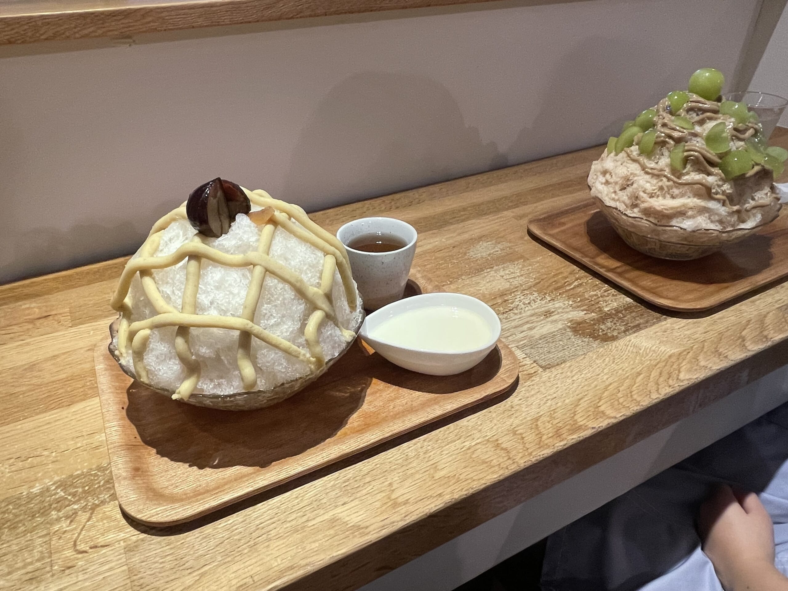 カフェクノップゥの「和栗ミルク」かき氷と「シャインマスカットアールグレー」のかき氷がカウンターで並んでいる写真。