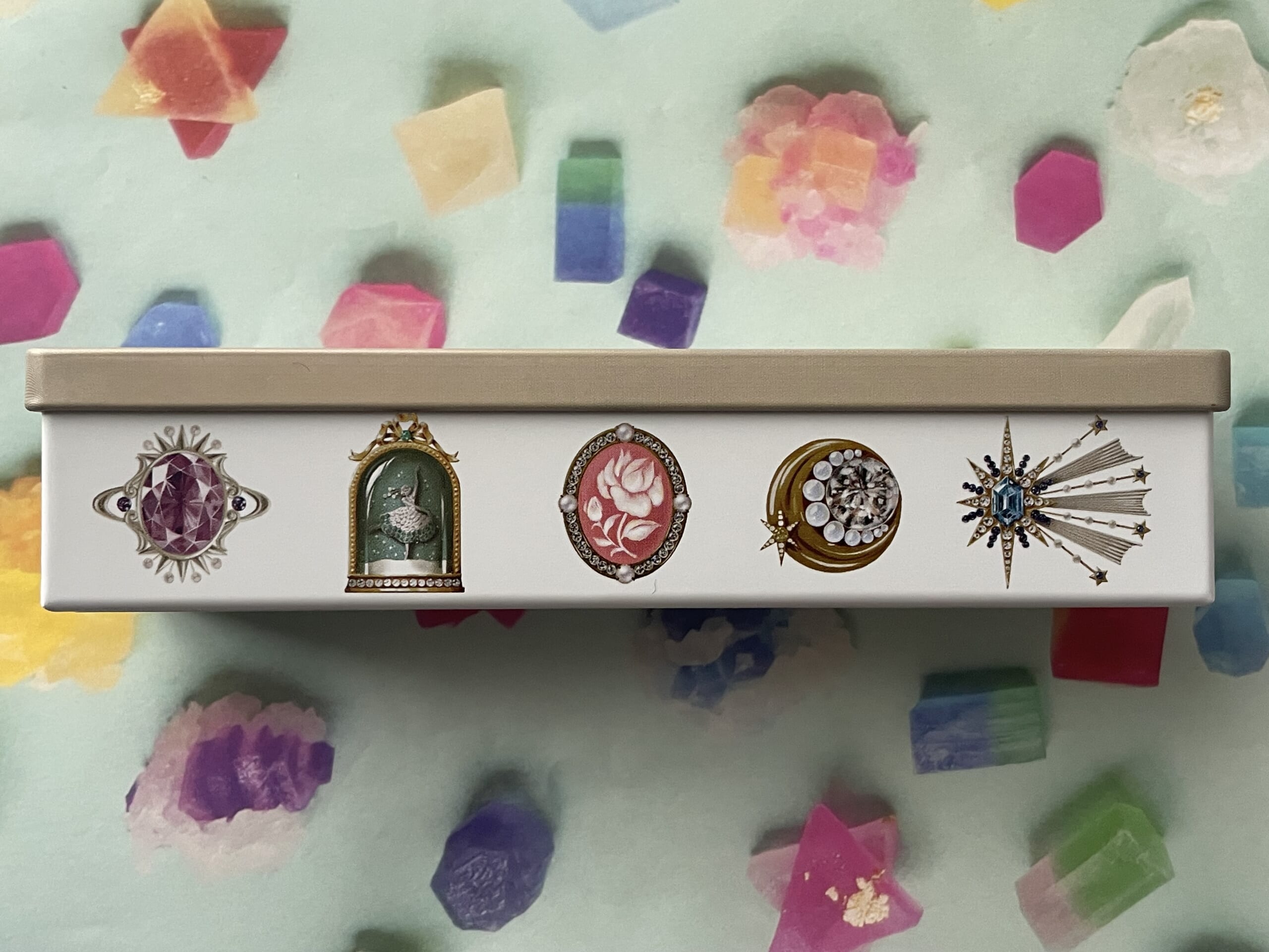 「宝塚すみれクッキー」のクッキー缶を真横から撮った写真。宙組、雪組、花組、月組、星組を表しているモチーフが並んでいる。