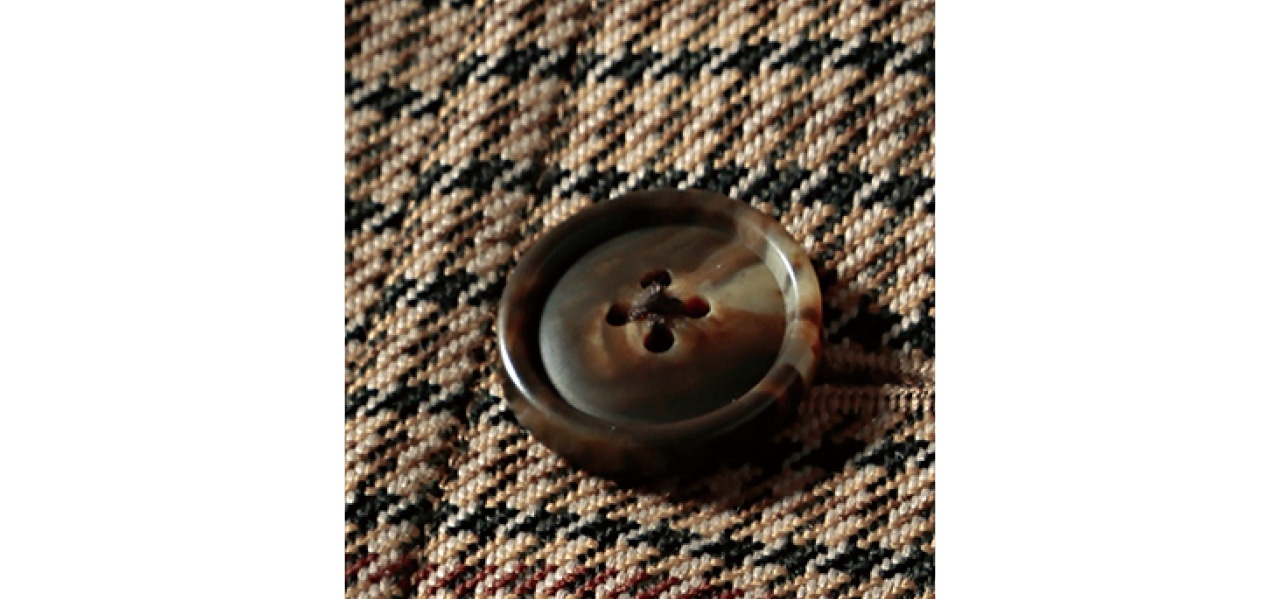 ブラウンにベージュ、黒、白で構成されたガンクラブチェックと、マーブル模様のブラウンボタンが、トラッドなムードを盛り上げて。