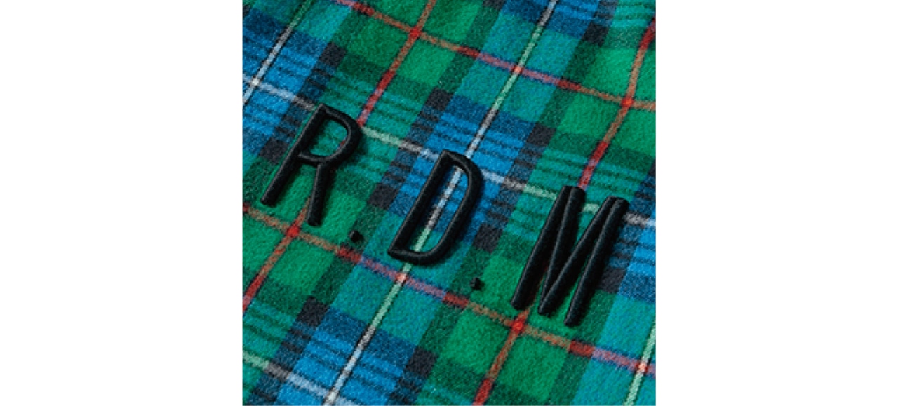 ほのかな起毛感のあるグリーンチェックのフランネル生地に、黒糸によるぷくっと立体的な刺しゅうロゴをオン。