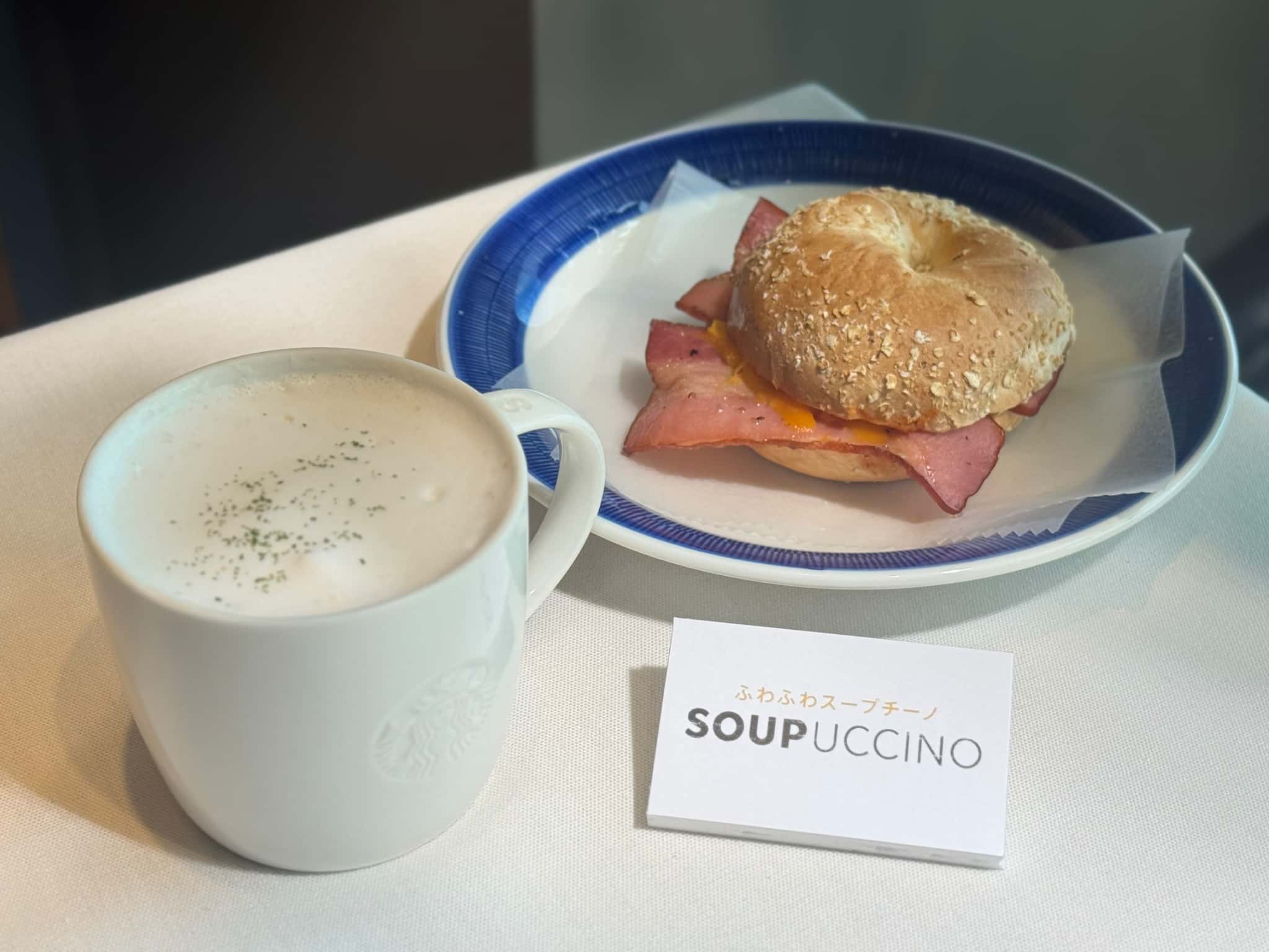 机の上に置かれた「トリュフ スープチーノ」と「ベーコンエッグチーズ ベーグルサンド」