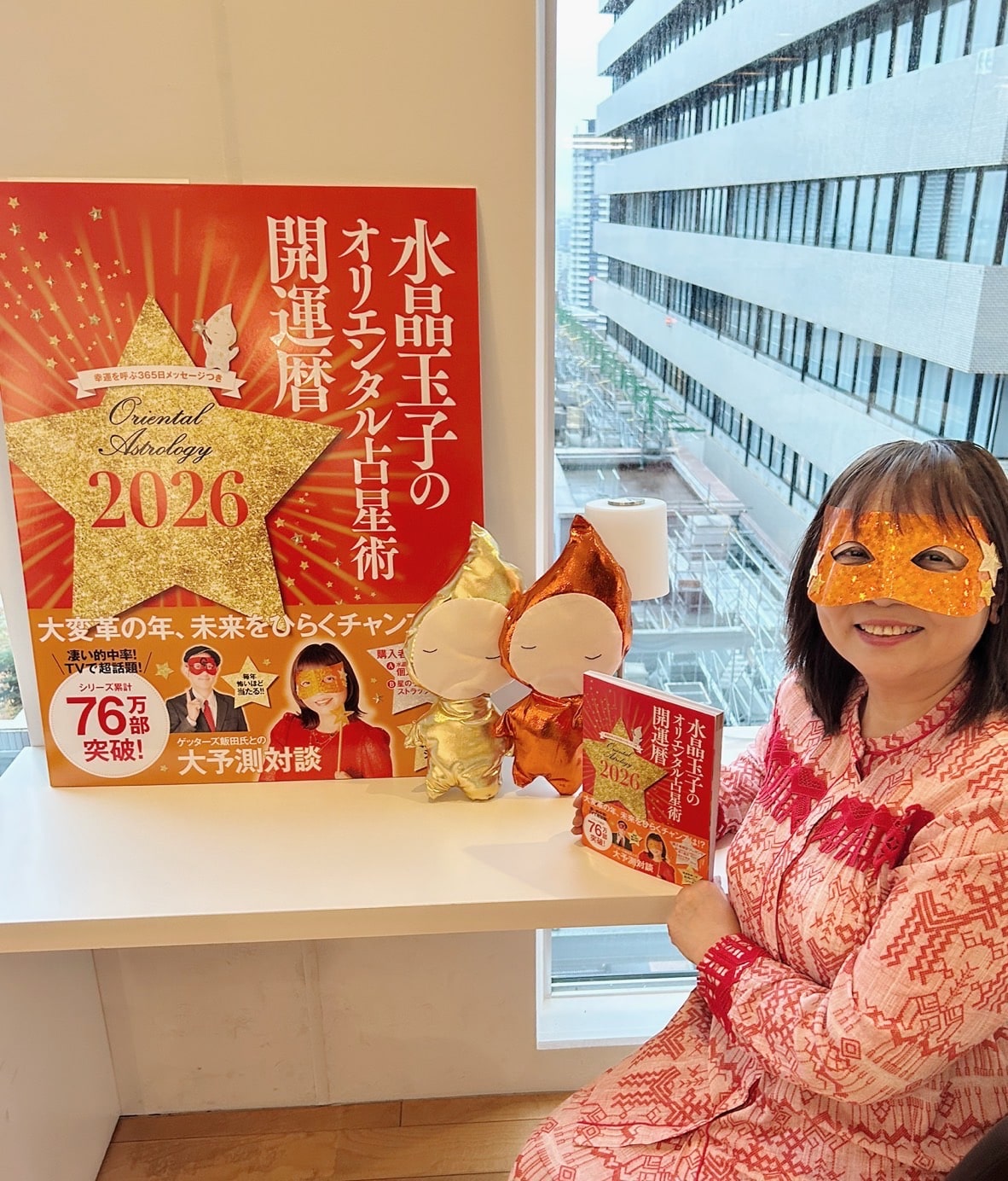 『水晶玉子のオリエンタル占星術　開運暦2026』を手に持つ水晶玉子先生