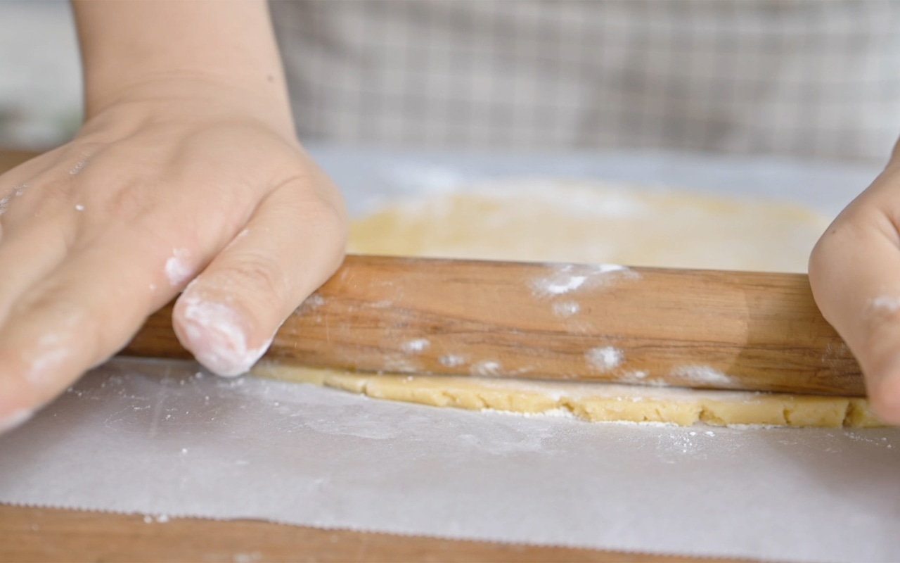 調理台にオーブンペーパーを敷いて打ち粉をし、③の生地をめん棒で5mmの厚さに伸ばす。生地を好みの型で抜き、オーブンペーパーを敷いた天板に型抜きをしたクッキーを丁寧に置く。