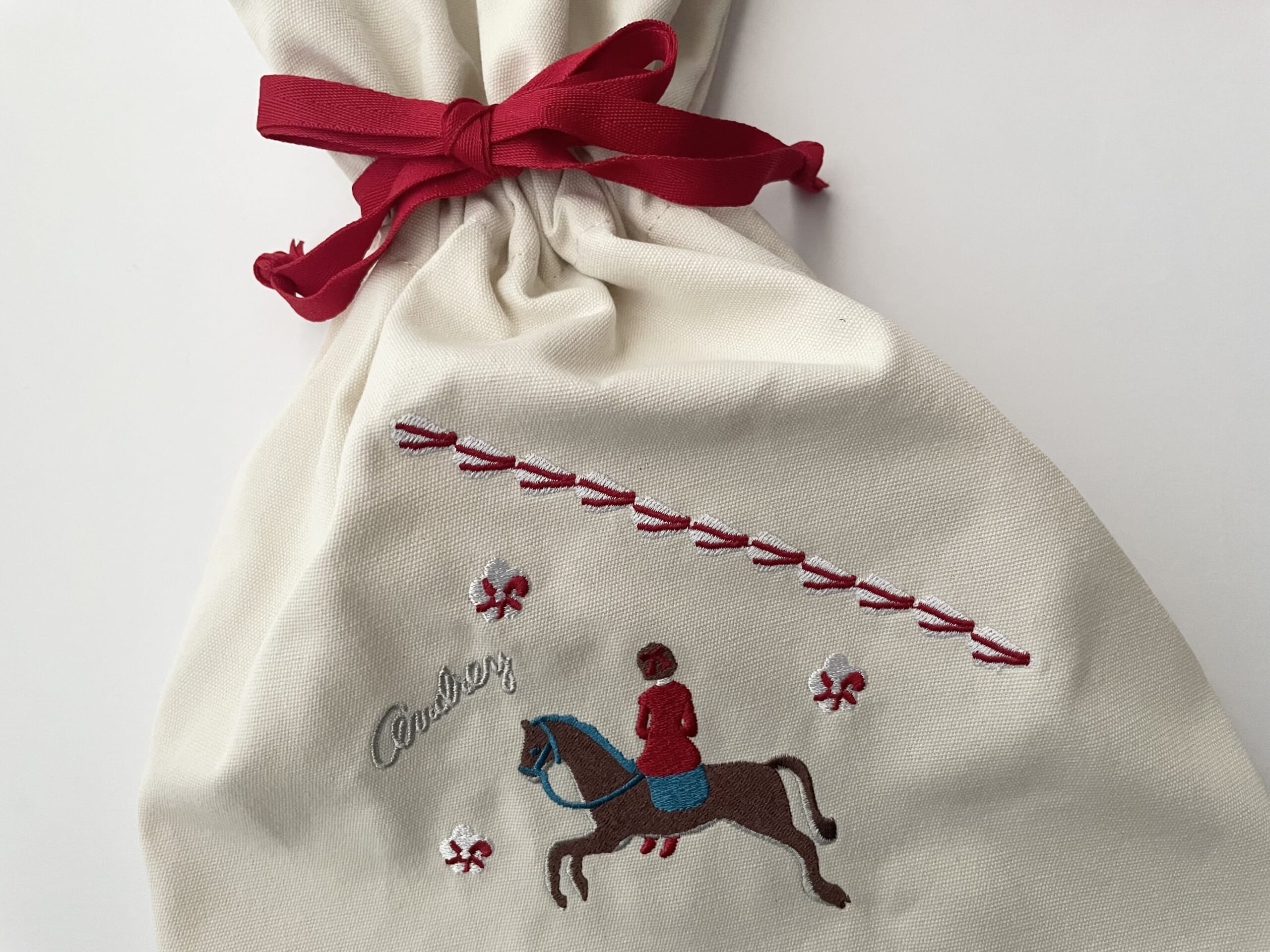 オードリー巾着2025の写真。白地の布に刺繍が施されている。