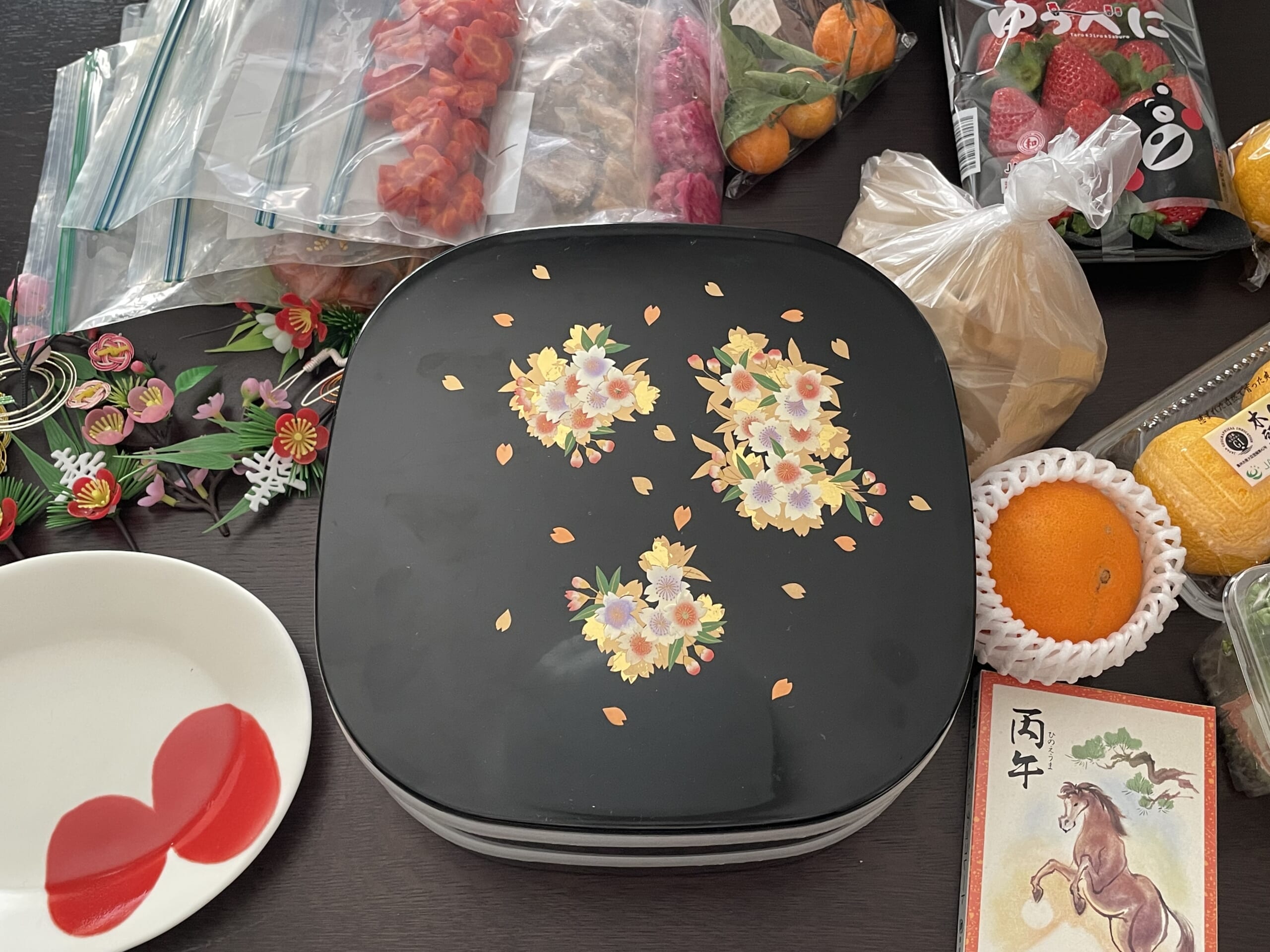 2段重とおせち料理のストック、食卓に並べる器が雑然と机の上に置いてある写真