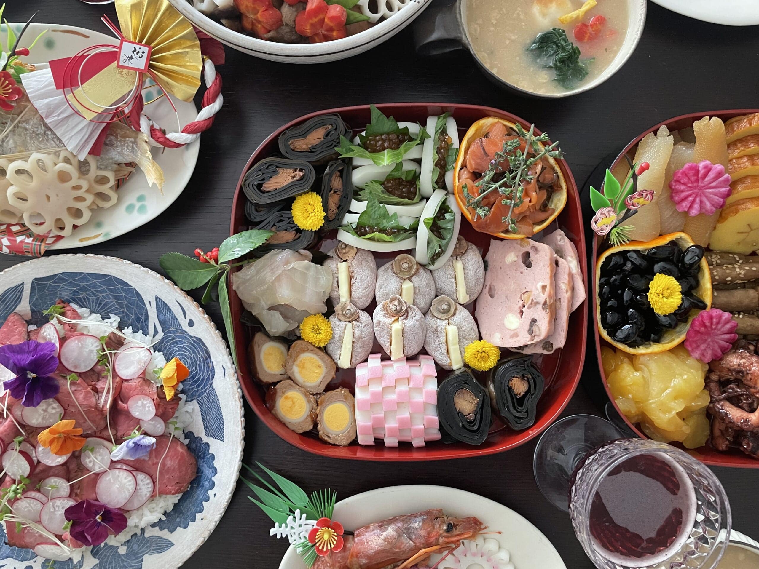 二の重。鮭の昆布巻き、いくらのかまぼこ宝舟、サーモンの塩昆布和え、鯛の昆布〆、干し柿のバターはさみ、ナッツケーゼ、うずら卵の肉巻き、紅白かまぼこ、にしんの昆布巻きが詰められている。