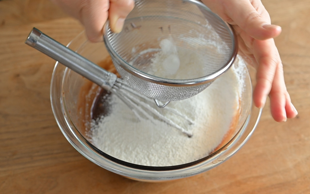 ①がすべて滑らかに溶けたら、卵と砂糖を入れて泡立て器で混ぜ、ホットケーキミックスをふるって加え、泡立て器でさっくりと混ぜ合わせる。