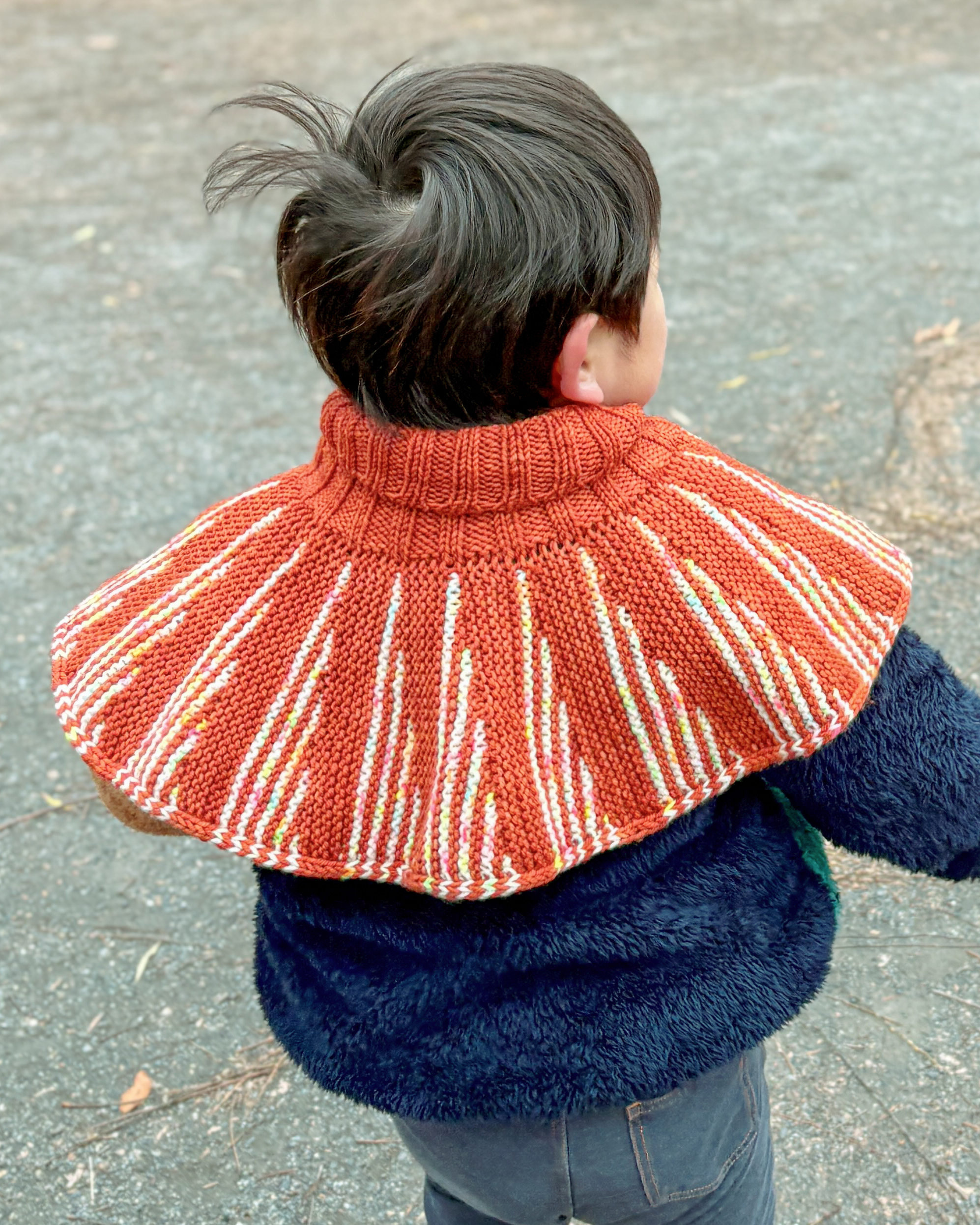 LEEスタッフのねこまが編んだ赤いニットポンチョを着た男の子